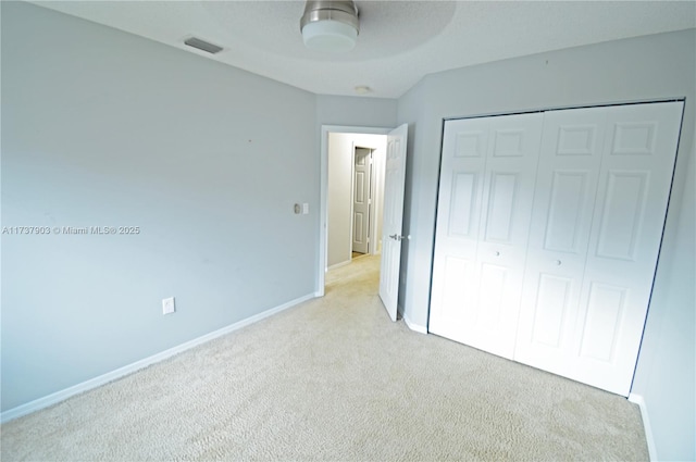 unfurnished bedroom with light carpet, ceiling fan, and a closet