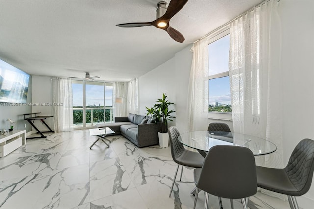 dining area featuring ceiling fan, a textured ceiling, expansive windows, and a healthy amount of sunlight