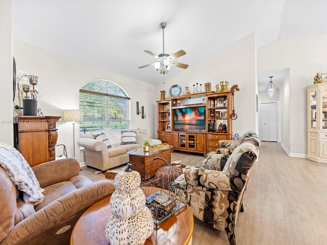 living room with ceiling fan, vaulted ceiling, and light wood-type flooring