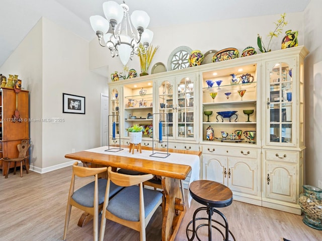 dining space with lofted ceiling, a chandelier, and light hardwood / wood-style floors