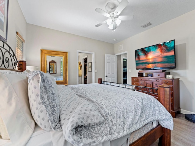 bedroom with ceiling fan, a walk in closet, and light hardwood / wood-style floors