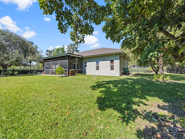 rear view of property with a lawn and a sunroom