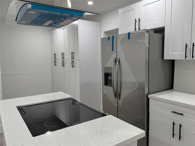 kitchen featuring light stone counters, stove, stainless steel fridge with ice dispenser, and white cabinets