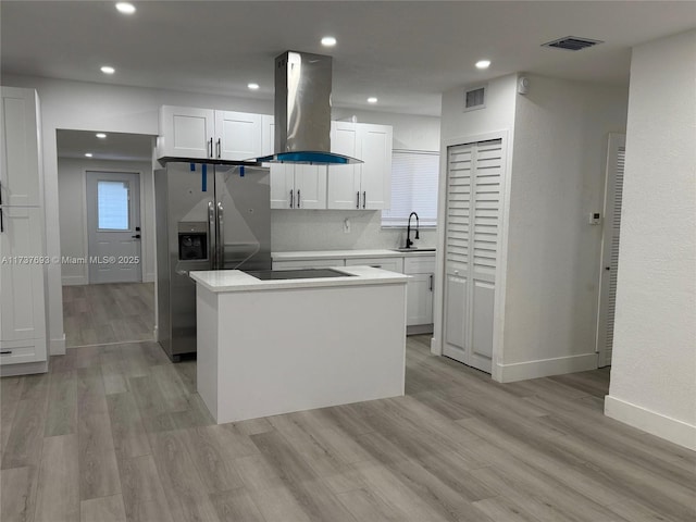 kitchen with sink, white cabinetry, island range hood, light hardwood / wood-style flooring, and a kitchen island