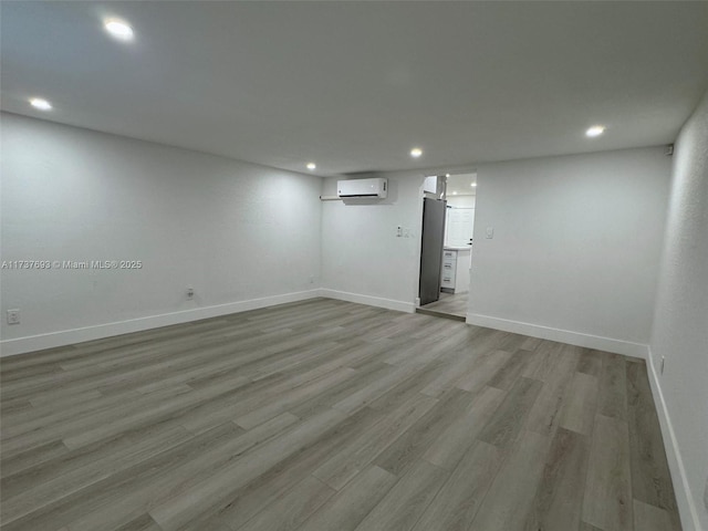 basement featuring light hardwood / wood-style floors and an AC wall unit