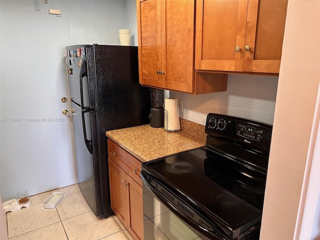 kitchen featuring light stone counters, light tile patterned floors, and black appliances