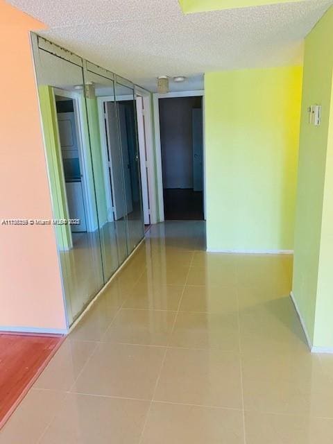 corridor featuring tile patterned flooring and a textured ceiling