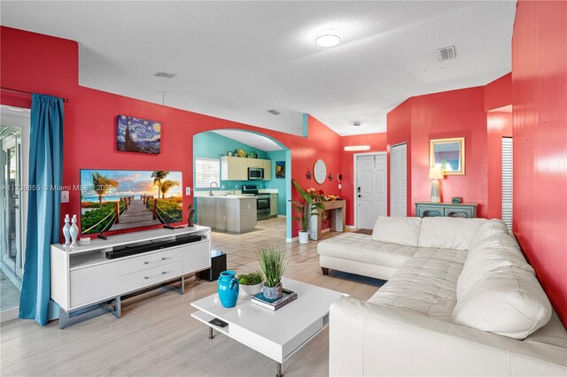 tiled living room with ceiling fan, vaulted ceiling, and a textured ceiling