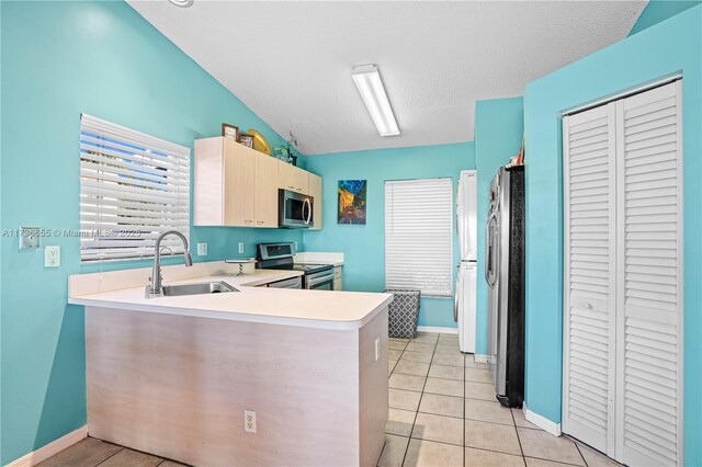 kitchen with stainless steel appliances, light tile patterned flooring, and lofted ceiling