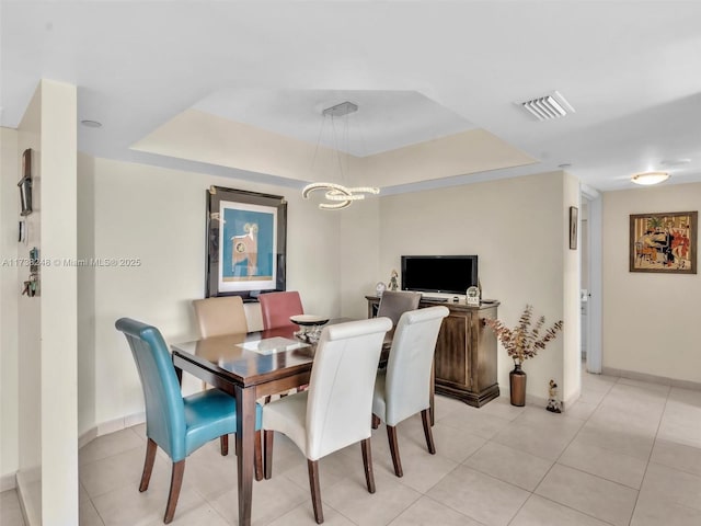 dining room featuring light tile patterned floors, a tray ceiling, visible vents, and baseboards