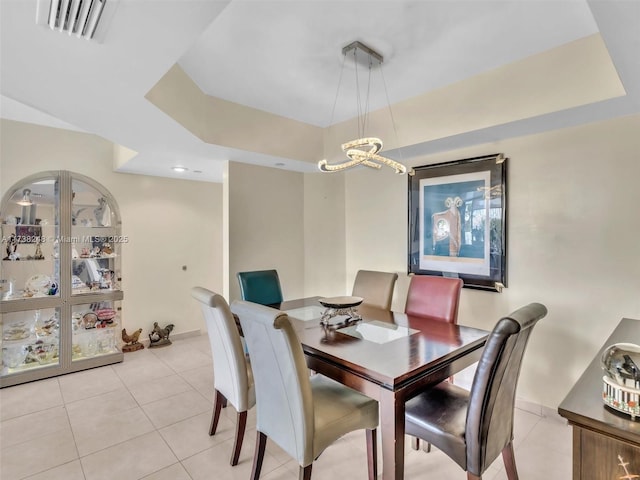 dining space with light tile patterned floors, a tray ceiling, visible vents, and a notable chandelier