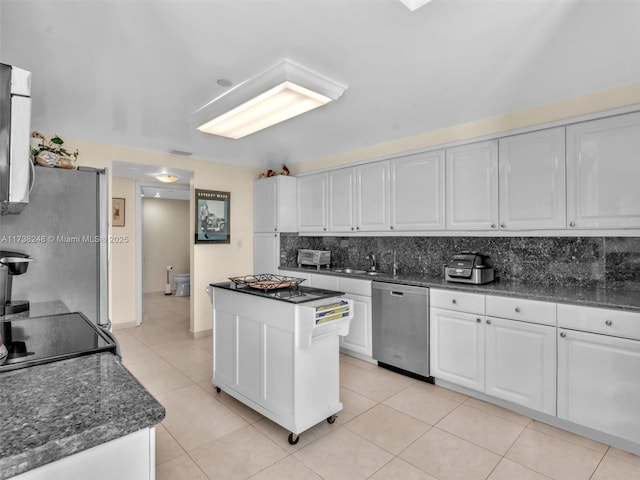 kitchen featuring a center island, stainless steel appliances, tasteful backsplash, white cabinets, and light tile patterned flooring