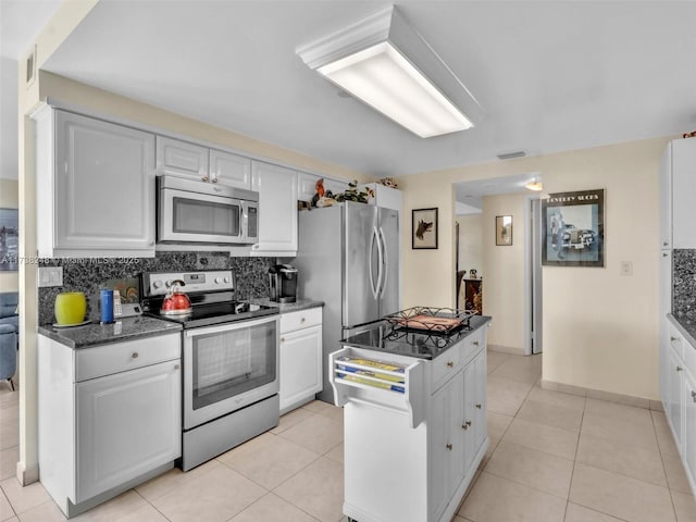 kitchen featuring stainless steel appliances, light tile patterned floors, white cabinets, and tasteful backsplash