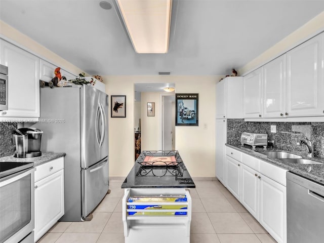 kitchen with light tile patterned floors, a sink, white cabinetry, appliances with stainless steel finishes, and decorative backsplash