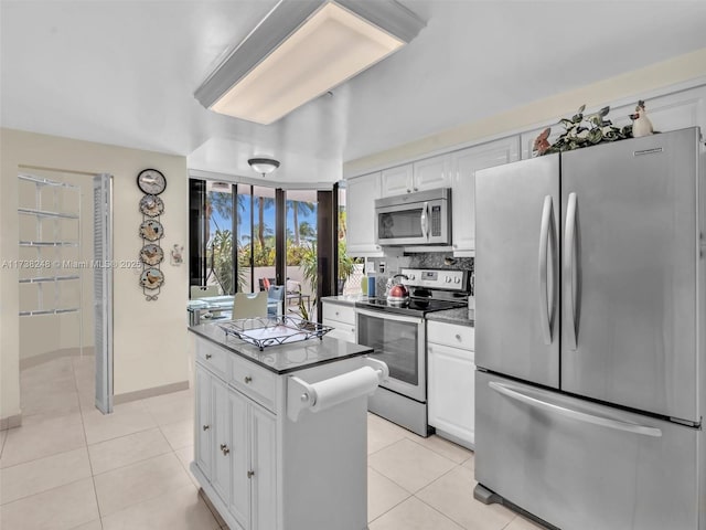 kitchen with light tile patterned floors, stainless steel appliances, dark countertops, and white cabinets