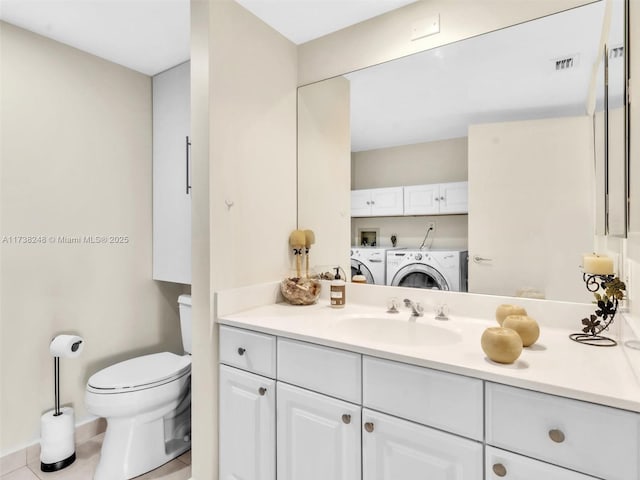 bathroom featuring visible vents, toilet, washing machine and dryer, vanity, and tile patterned flooring