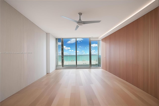 spare room with ceiling fan, floor to ceiling windows, and light hardwood / wood-style flooring