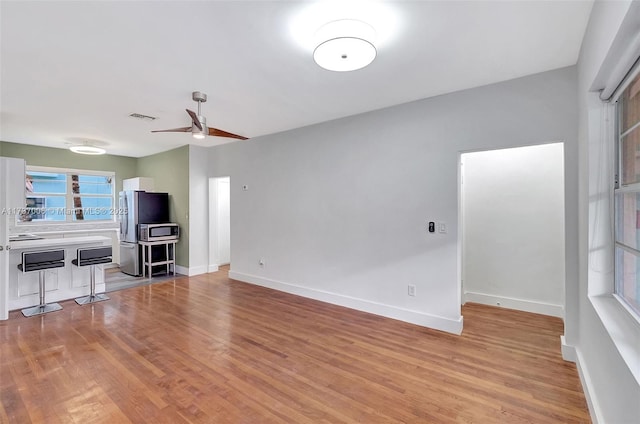 unfurnished living room featuring ceiling fan and light hardwood / wood-style flooring