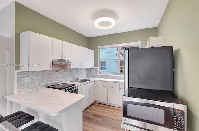 kitchen with a kitchen breakfast bar, stainless steel appliances, kitchen peninsula, and white cabinets