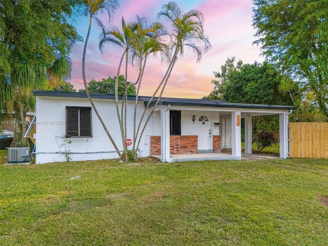 view of front of property featuring covered porch, fence, a front lawn, and central AC unit