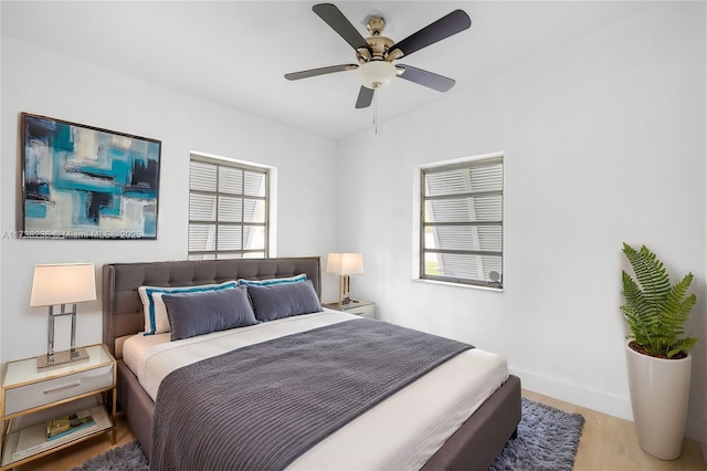 bedroom with ceiling fan, baseboards, and wood finished floors