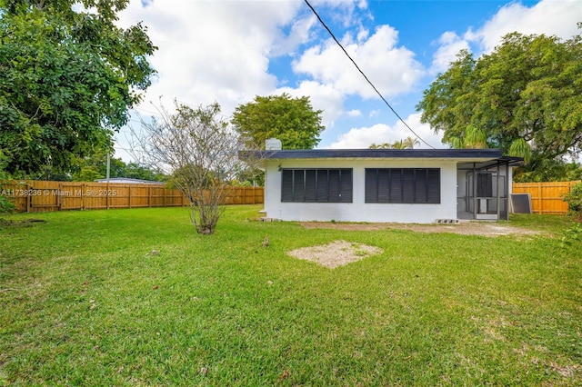 rear view of property with a fenced backyard and a yard