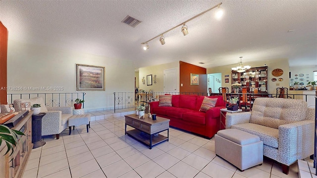living room featuring an inviting chandelier, light tile patterned floors, rail lighting, and a textured ceiling