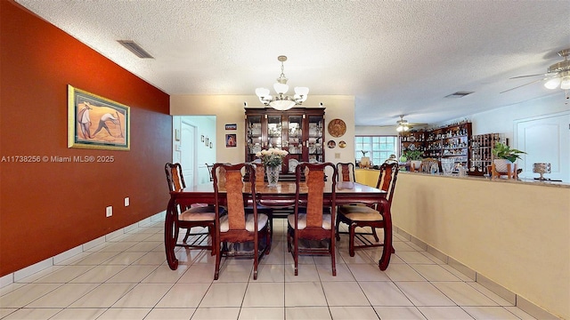 dining area featuring light tile patterned flooring, ceiling fan with notable chandelier, and a textured ceiling