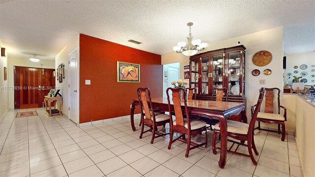 dining space featuring an inviting chandelier, a textured ceiling, and light tile patterned flooring