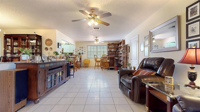 living room featuring light tile patterned flooring, ceiling fan, and a textured ceiling