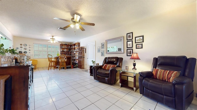 tiled living room with ceiling fan, indoor bar, and a textured ceiling