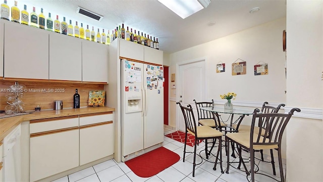 kitchen with wooden counters, light tile patterned floors, white cabinets, and white appliances