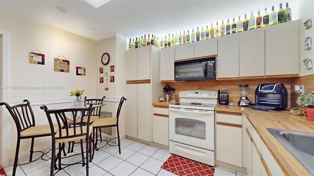 kitchen featuring wood counters, white electric stove, sink, and light tile patterned floors