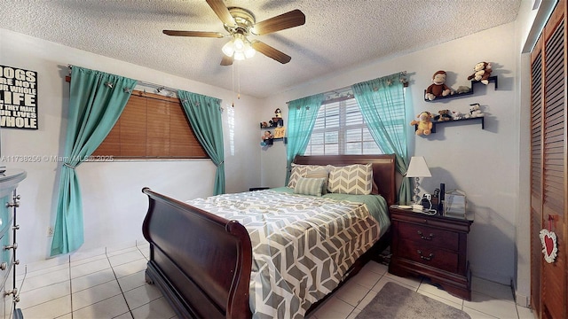 tiled bedroom with ceiling fan and a textured ceiling