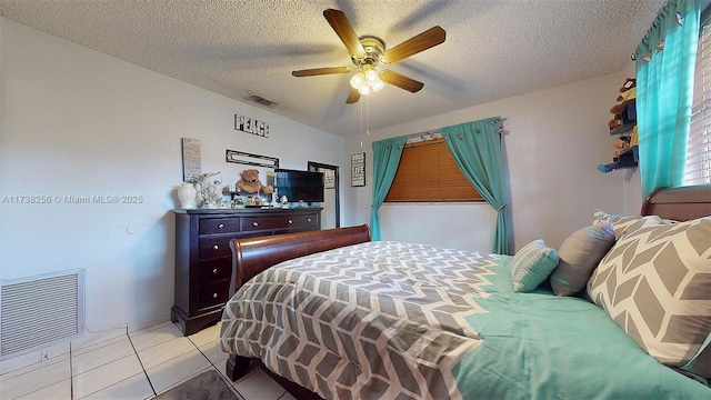 bedroom with ceiling fan, light tile patterned floors, and a textured ceiling
