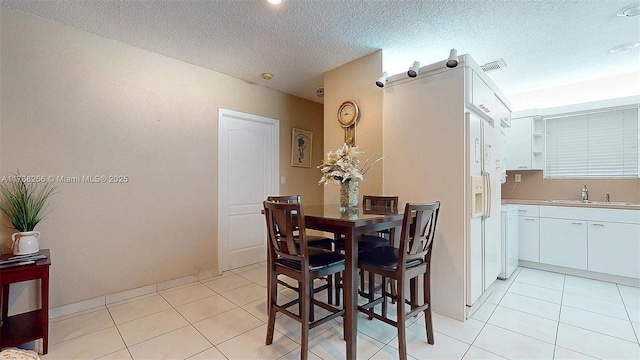 dining space featuring sink, a textured ceiling, and light tile patterned floors