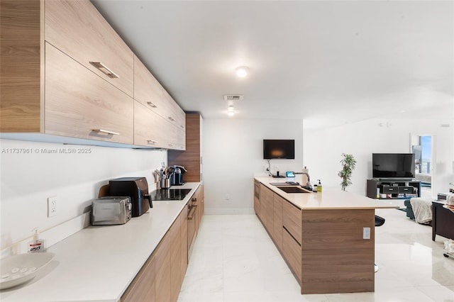 kitchen featuring a kitchen island, sink, and black electric cooktop