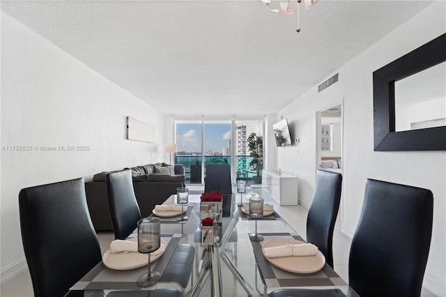 dining area with expansive windows, a textured ceiling, visible vents, and baseboards