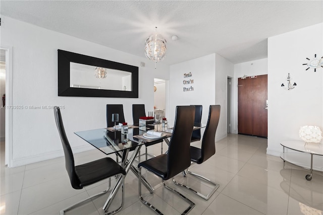 tiled dining space with a notable chandelier, a textured ceiling, and baseboards