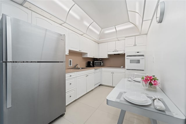 kitchen featuring light tile patterned floors, appliances with stainless steel finishes, light countertops, white cabinetry, and a sink