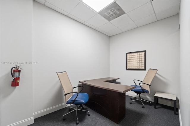 carpeted home office with a paneled ceiling and baseboards