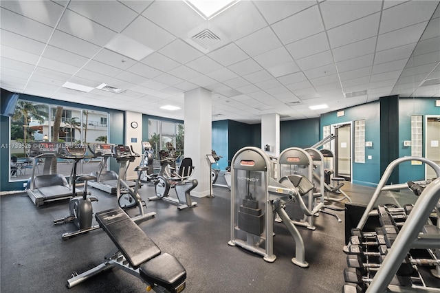 gym featuring a wealth of natural light, a drop ceiling, visible vents, and baseboards