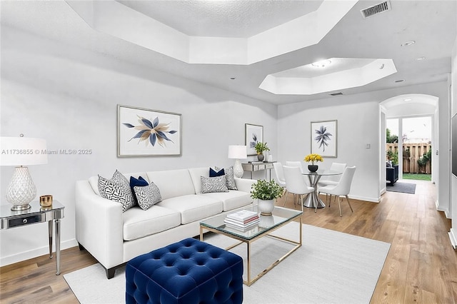 living room with a tray ceiling, hardwood / wood-style floors, and a textured ceiling