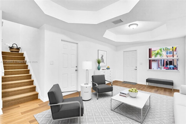 kitchen featuring white appliances, white cabinetry, a center island, a tray ceiling, and light hardwood / wood-style floors