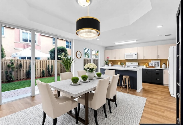 dining area featuring a tray ceiling and light wood-type flooring