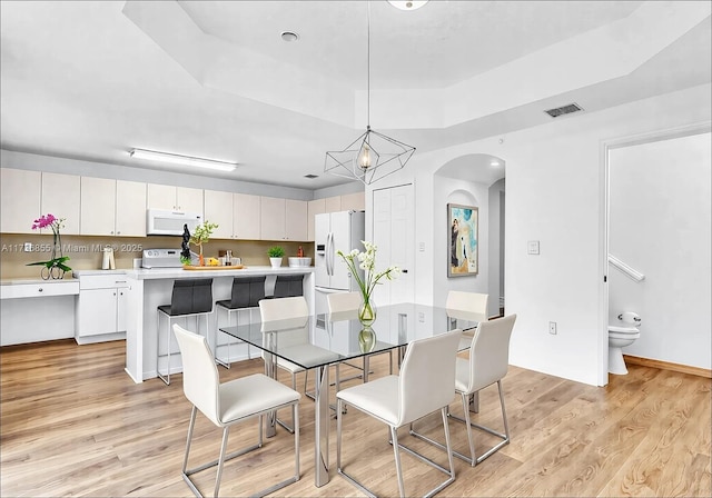 kitchen with white appliances, light hardwood / wood-style flooring, a kitchen island, and white cabinets