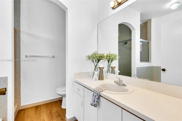 bathroom featuring wood-type flooring, vanity, an enclosed shower, and toilet