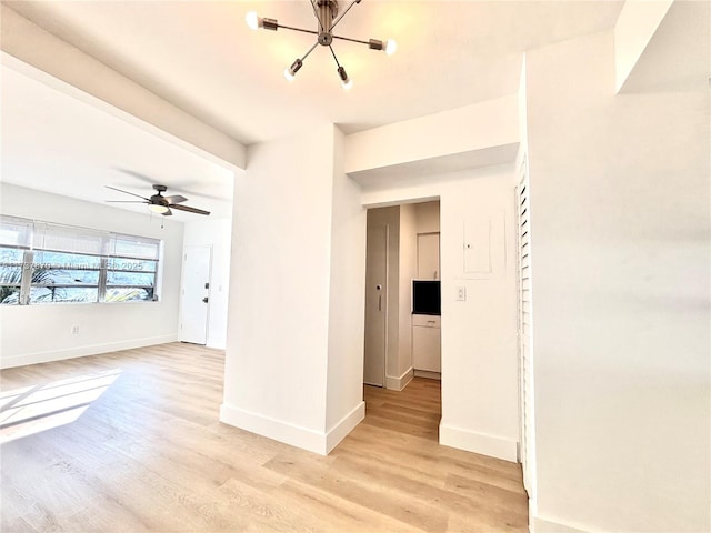 spare room with ceiling fan with notable chandelier and light wood-type flooring