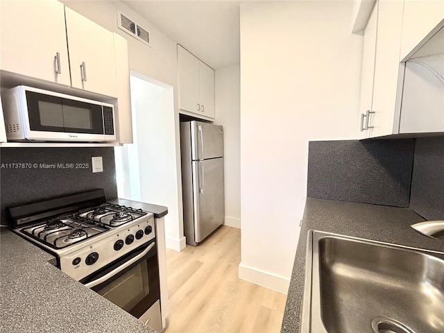 kitchen with sink, stainless steel fridge, light hardwood / wood-style flooring, white cabinetry, and range with gas cooktop