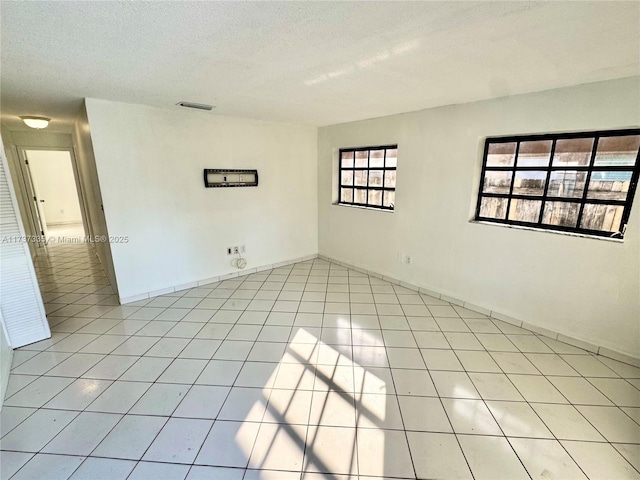 spare room with a textured ceiling and light tile patterned floors